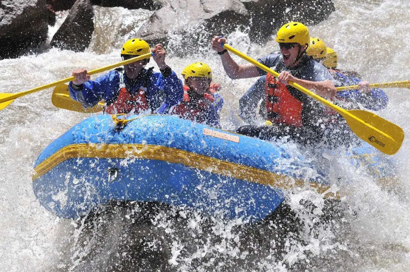 WAO colorado whitewater family rafting trip. family paddling through a rapid with a rafting guide